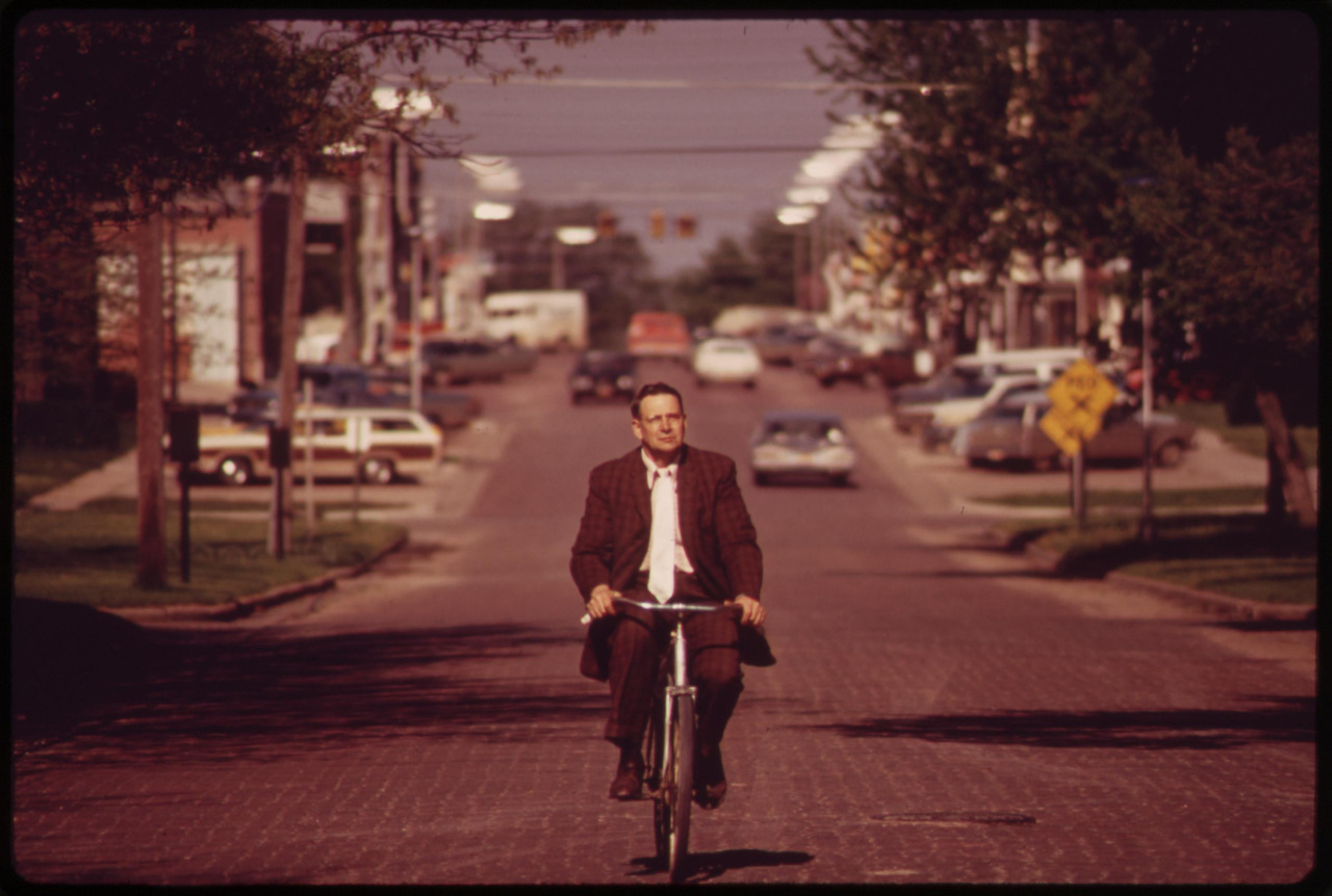 A man in a suit, casually cycling on a quiet road