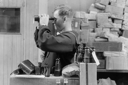 A man at a desk, looking through binoculars