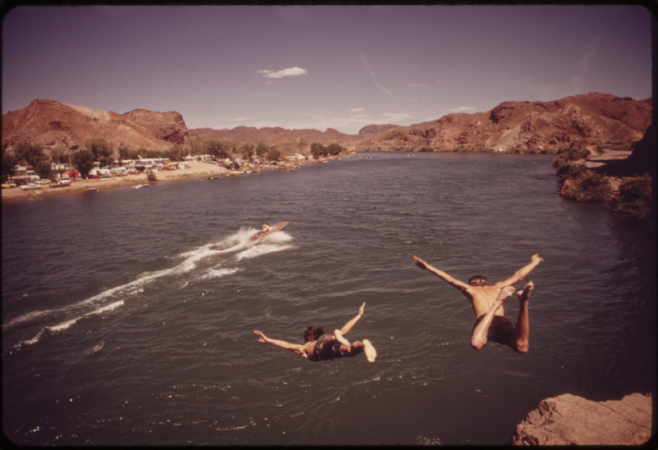 Two people diving into huge river on a sunny day